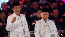 Indonesian President Joko Widodo, left, delivers a speech with running mate Ma'ruf Amin, right, during a televised debate in Jakarta, Indonesia, Thursday, Jan. 17, 2019. 
