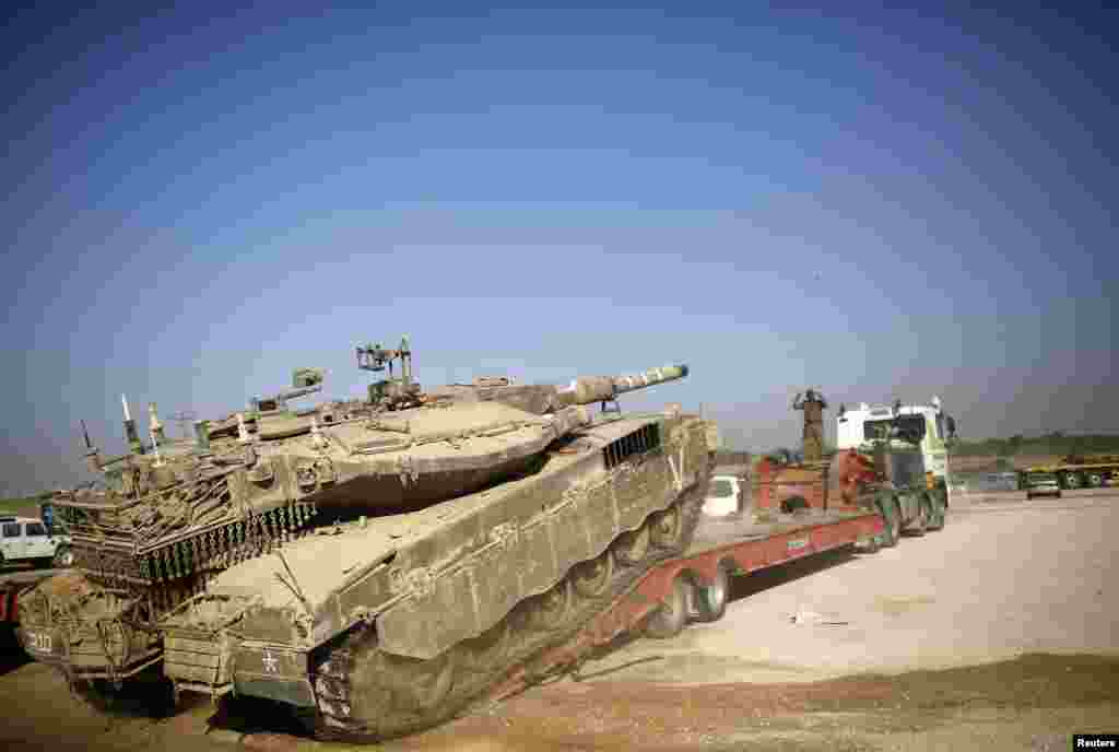An Israeli soldier directs a tank onto a truck for transport near the border with Gaza, Aug. 6, 2014.