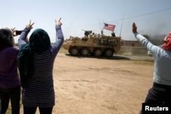 People gesture at a U.S military vehicle travelling in Amuda province, northern Syria, April 29, 2017.