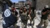 FILE - Members of the Emergency Response Division, the elite strike force of Iraq's Interior Ministry, hold an IS flag that they pulled down as they celebrate in Mosul, Iraq, July 8, 2017. Iraqi security forces continue to battle pockets of resistance across the country.