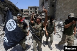 Members of the Emergency Response Division hold an Islamic State flag that they pulled down as they celebrate in the Old City of Mosul, Iraq, July 8, 2017.