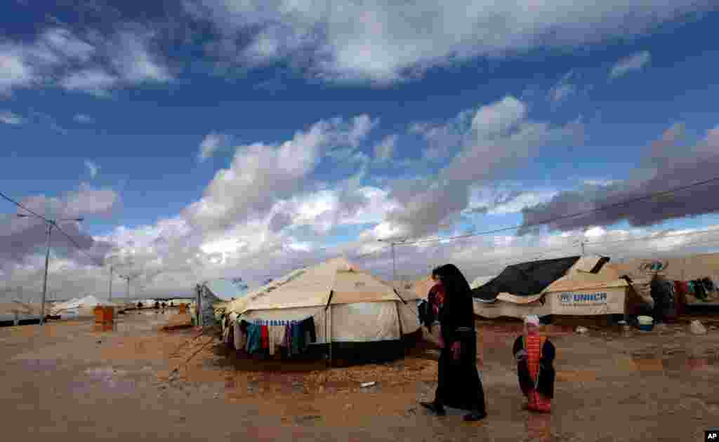 A Syrian refugee woman walks with her children at Zaatari Syrian refugee camp, near the Syrian border in Mafraq, Jordan, January 9, 2013.