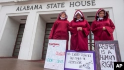 Bianca Cameron-Schwiesow, from left, Kari Crowe and Margeaux Hartline, dressed as handmaids, take part in a protest against HB314, the abortion ban bill, at the Alabama State House in Montgomery, Ala., on Wednesday April 17, 2019. (Mickey Welsh/The Montgo
