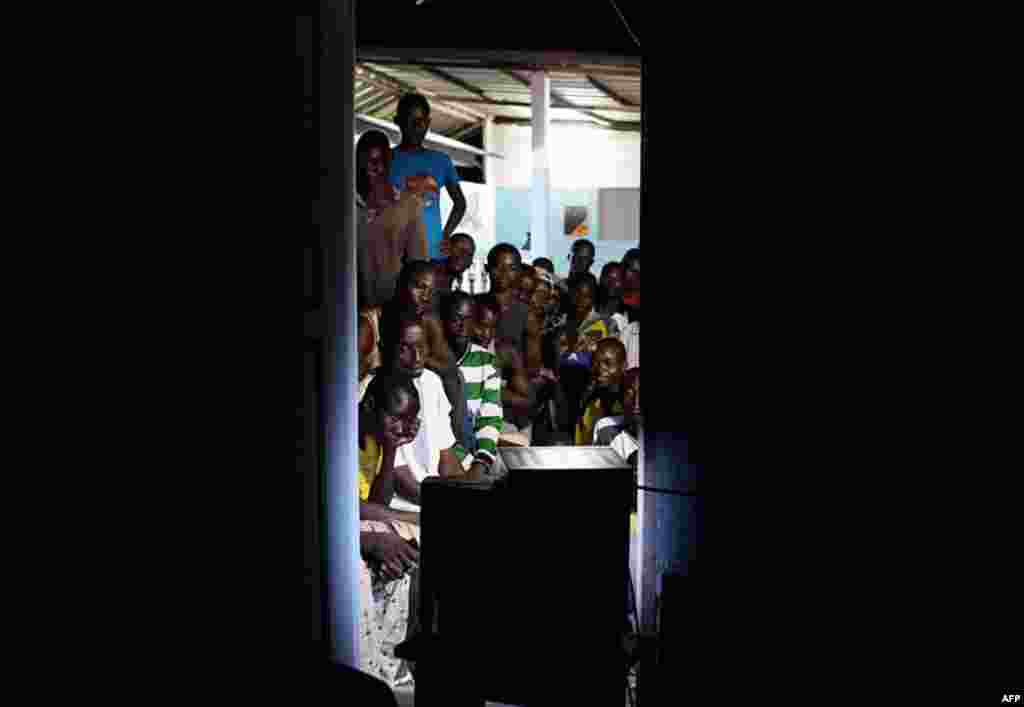 April 11: Local residents gather around a TV as they wait for the start of an address by leader Alassane Ouattara, hours after the capture of strongman Laurent Gbagbo, in the village of Kossihen, outside Abidjan, Ivory Coast. (AP Photo/Rebecca Blackwell)