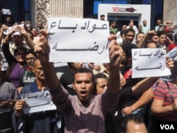 Egyptian protesters hold a sign that says "Awad sold his land" in Arabic during protest against the transfer of power of two Red Sea islands from Egypt to Saudi Arabia in downtown Cairo, April 15, 2016. The Egyptian proverb refers to shame some locals fee