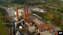 The smokestacks of the Greenidge Generation power plant tower above nearby homes, Friday, Oct. 15, 2021, in Dresden, N.Y. A Bitcoin mining operation in central New York came up with a solution to finding cheap energy to run the power-gobbling computer arr