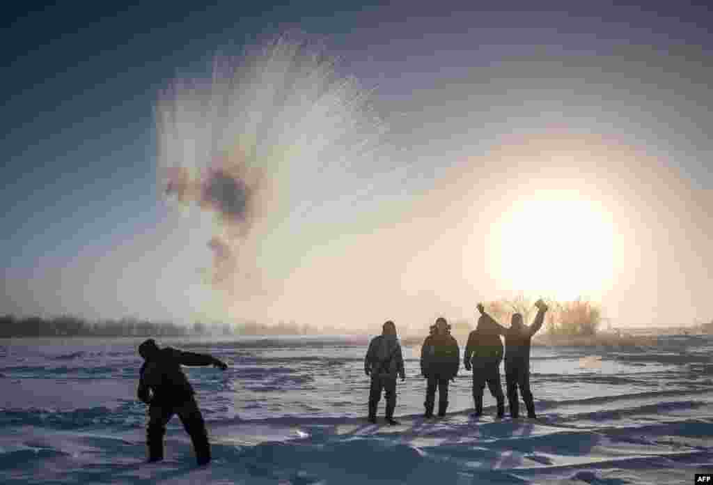 A villager throws hot water into the air while harvesting ice from a local lake near the settlement of Oy, some 70 km south of Yakutsk, Russia, Nov. 27, 2018, with the air temperature at about -41&deg; C (-41.8&deg; F).