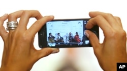 A journalist takes a photo using a smart phone during a press conference, file photo. 