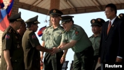 FILE - Cambodian Defense Minister Tea Banh, second left, shakes hands with a Chinese army adviser during a graduation ceremony at the Army Institute in Kampong Speu province, March 12, 2015. 