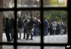 People line up outside a polling station to cast their vote for the Catalan regional election in Barcelona, Spain, Thursday, Dec. 21, 2017.