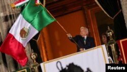El presidente de México, Andrés Manuel López Obrador, ondea la bandera durante la ceremonia de "El grito de independencia" en el Palacio Nacional de la Ciudad de México el 15 de septiembre de 2021.