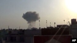 This image taken from video provided by the Syrian activist-based media group Qasioun News, which has-been verified and is consistent with other AP reporting, shows smoke rising from a Syrian government airstrike, in Douma, rural Damascus, Syria. 