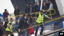 Des agents de l'agence de protection des frontières de l'Union européenne, Frontex, mènent un migrant dans un ferry dans le port de Mytilène, l'île de Lesbos, en Grèce, le 8 Avril 2016.(AP Photo/Petros Giannakouris)