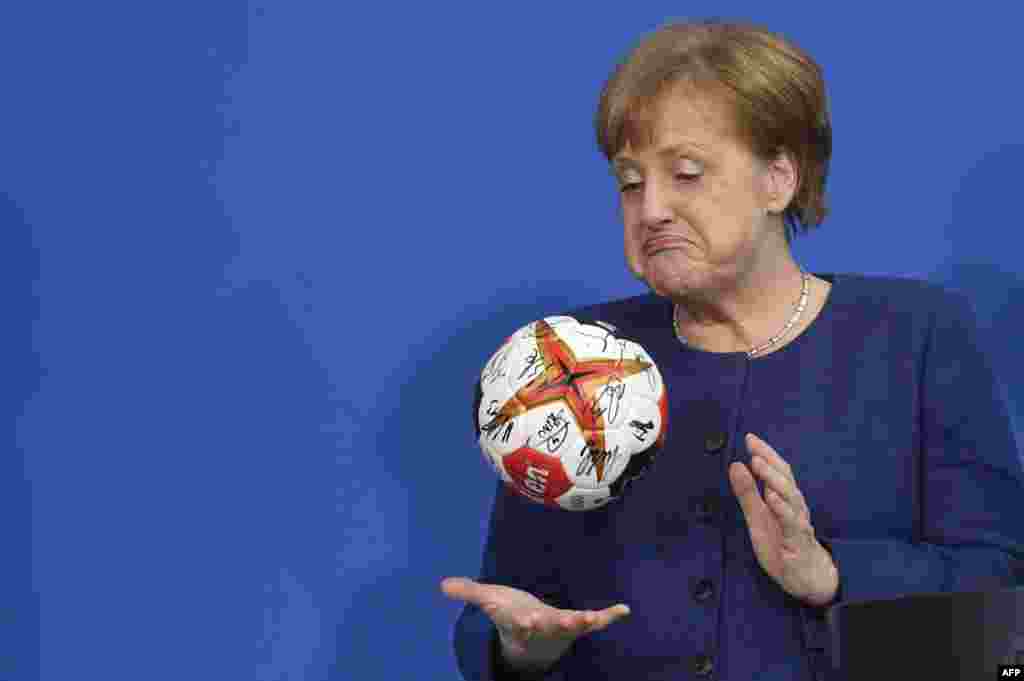 German Chancellor Angela Merkel plays with a handball given to her by the German Handball Federation&#39;s president at the Chancellery in Berlin.