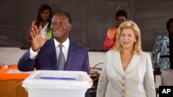 Ivory Coast’s president Alassane Ouattara, left, waves after casting his ballot with his wife, Dominique Ouattara, right, at a polling station during elections in Abidjan, Ivory Coast, Sunday Oct. 25, 2015. 