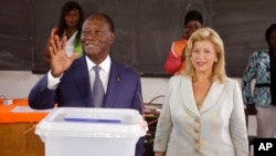 Presiden Pantai Gading Alassane Ouattara (kiri) setelah memberikan suaranya di sebuah TPS bersama istrinya Dominique Ouattara, di Abidjan (25/10). (AP/Schalk van Zuydam)