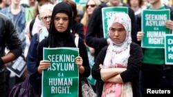 FILE - A woman holds a poster during a rally in support of asylum seekers in central Sydney.