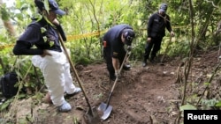 Members of the attorney general's forensic team dig for a supposed grave after handcuffed ex-rebels pointed out the location in a rural area close to Chaguani, Colombia, June 18, 2015.