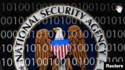 FILE - A tablet computer shows the logo of the United States' National Security Agency (NSA) against the backdrop of code in this multiple-exposure demonstration photo. 