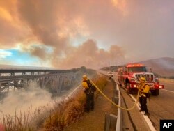 Petugas pemadam kebakaran berupaya memadamkan api kebakaran di tepi Highway 101 menuju selatan Vista Point, Selasa sore, 12 Oktober 2021.