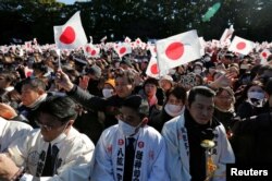 Warga Jepang melambaikan bendera Jepang dan meneriakkan “Banzai” saat Kaisar Jepang Akihito dan anggota keluarga kerajaan tampil dalam perayaan Tahun Baru di Istana Kekaisaran di Tokyo, Jepang, 2 Januari 2019.