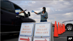 Një punonjëse e bashkisë mbledh votat me postë në një zonë të caktuar për njerëzit që dorëzojnë votën nga makina (Qarku Clark, Las Vegas, 2 nëntor 2020)