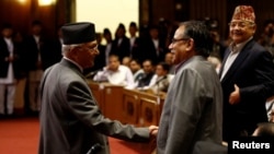 Nepal's Prime Minister Khadga Prasad Sharma Oli, also known as KP Oli, shakes hand with Chairman of the Unified Communist Party of Nepal (Maoist) Pushpa Kamal Dahal, also known as Prachanda, (R) as he returns after announcing his resignation at the parlia