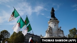 Un vélo avec des drapeaux algériens passe devant la statue de la place de la République à Paris, le 10 octobre 2021.
