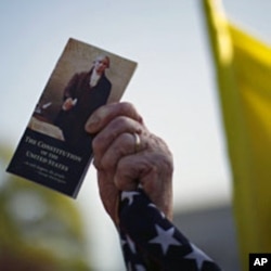 An opponent of U.S. President Barack Obama's healthcare law holds a copy of the nation's Constitution during the first day of legal arguments over the Affordable Care Act at the Supreme Court in Washington, March 26, 2012