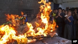 Tibetan exiles pray next to the burning funeral pyre of 27-year-old Jamphel Yeshi, who died two days after he immolated himself in Dharmsala, India, March 30, 2012. 