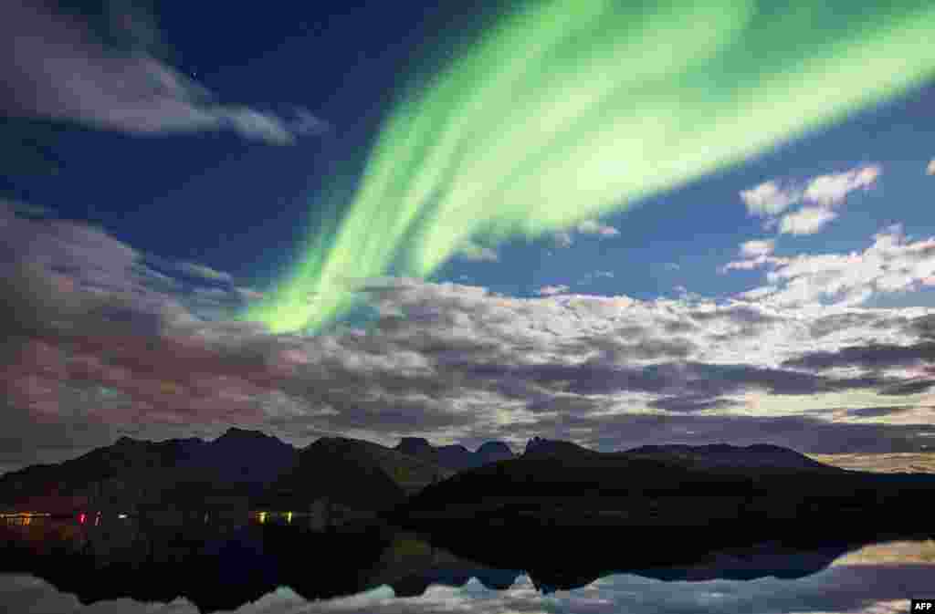 Northern lights (aurora borealis) illuminate the sky over Torsfjorden near Reine, on Lofoten Islands, Arctic Circle.