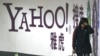 FILE - A woman walks past a Yahoo billboard in a Beijing subway station, March 17, 2006. Yahoo Inc. withdrew from the China market Nov. 1, 2021, because of an 'increasingly challenging' business and legal environment.