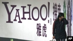 FILE - A woman walks past a Yahoo billboard in a Beijing subway station, March 17, 2006. Yahoo Inc. withdrew from the China market Nov. 1, 2021, because of an "increasingly challenging" business and legal environment.