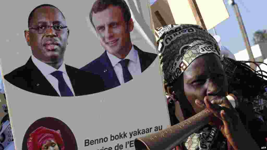 Un manifestant tient un tableau avec des photos du président sénégalais Macky Sall et du président français Emmanuel Macron avant l&#39;inauguration d&#39;un collège à Dakar, le 2 février 2018.