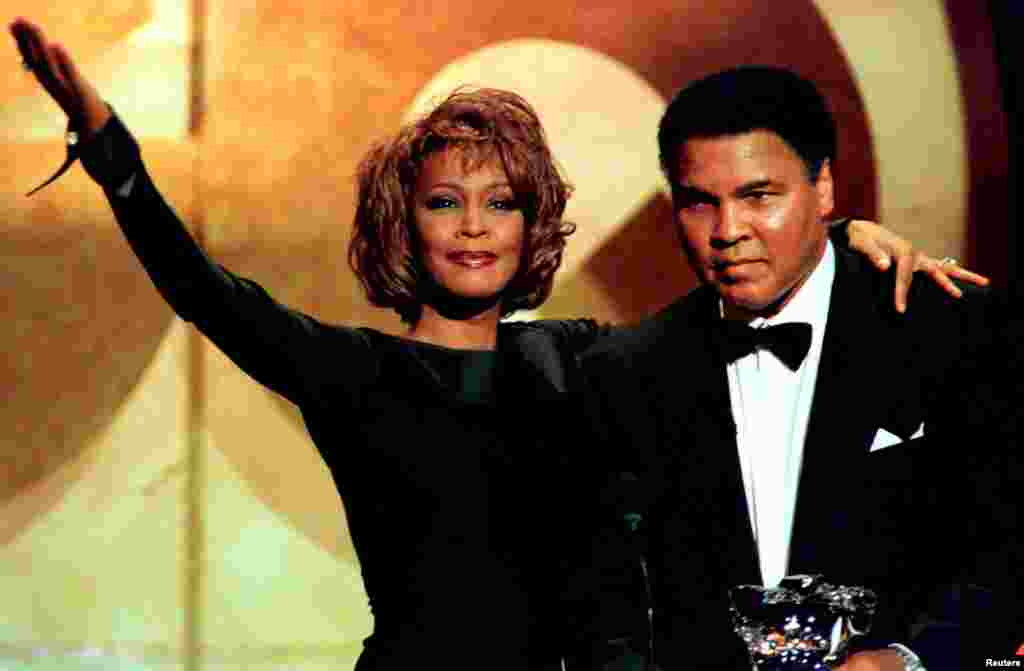 Former boxing great Muhammad Ali is given the Courage Award by singer Whitney Houston at the GQ Men of the Year awards show in New York in this October 21, 1998 file photo.