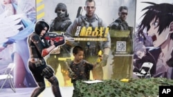 A child plays with a toy gun during a promotion for online games in Beijing on Saturday, Aug. 29, 2020. (AP Photo/Ng Han Guan)