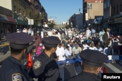 FILE - New York Police Department (NYPD) officers stand near worshippers as they gather outside the Masjid At-Taqwa mosque ahead of Eid Al-Adha prayers in the Brooklyn borough of New York, Sept. 24, 2015.