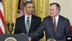 President Barack Obama stands with former President George H.W. Bush, as he prepares to present him with a 2010 Presidential Medal of Freedom during a ceremony in the East Room of the White House in Washington, February 15, 2011