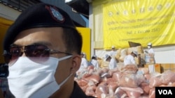 A policeman stands in front of pile of seized drugs during narcotics destruction ceremony in Thailand, 2004. 