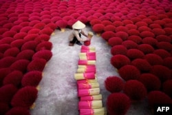 A Vietnamese woman collecting incense sticks in a courtyard in the village of Quang Phu Cau on the outskirts of Hanoi, Jan. 3, 2019.