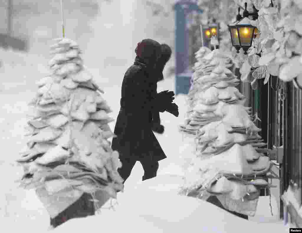 Seorang pejalan kaki kesulitan untuk berjalan di kaki lima saat badai salju lebat melanda Quebec City, Kanada. 