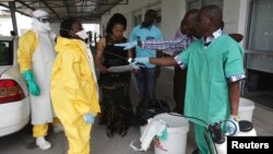 FILE - A health worker sprays a colleague with disinfectant during a training session for Congolese health workers to deal with Ebola virus in Kinshasa, Oct. 21, 2014. The process of removing the full-body protective suit is a prime opportunity for infection if the surface of the gear is contaminated.