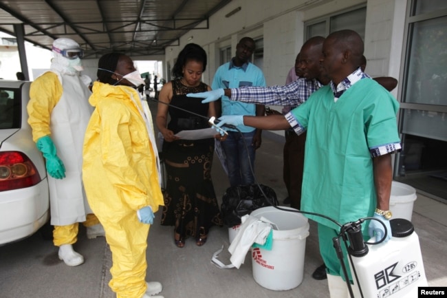 FILE - A health worker sprays a colleague with disinfectant during a training session for Congolese health workers to deal with Ebola virus in Kinshasa, Oct. 21, 2014.
