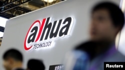 FILE — Visitors stand in front of a stall of the video surveillance product maker Dahua Technology at the Security China 2018 exhibition on public safety and security in Beijing, China, Oct. 23, 2018.