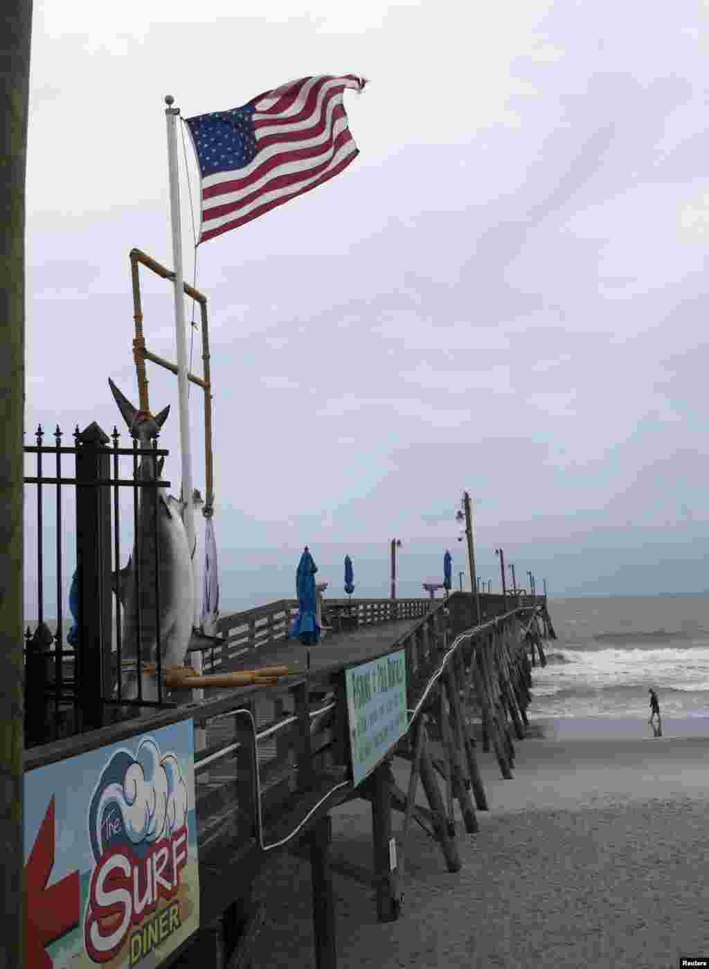 A man walks along the surf before the rains and outer bands of Hurricane Arthur move closer, in Surfside Beach, South Carolina, July 3, 2014.