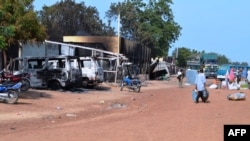People walk past vehicles and shops burnt by Boko Haram Islamists on a street of Benisheik, on Sept. 19, 2013.