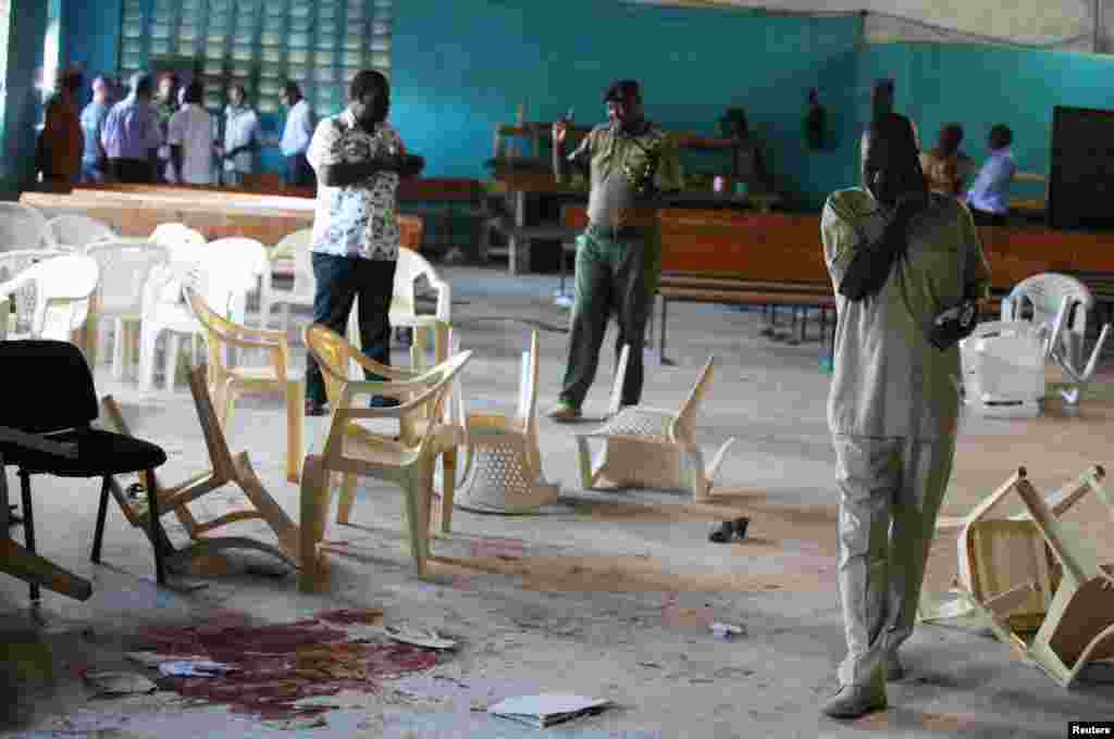 Plainclothes and uniformed Kenyan policemen inspect the scene of an attack by gunmen on worshippers while attending a church service, Mombasa, Kenya, March 23, 2014. 