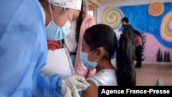 A health worker inoculates a child against COVID-19 with a dose of the CoronaVac vaccine, developed by China's Sinovac firm, in Quito on Oct. 18, 2021