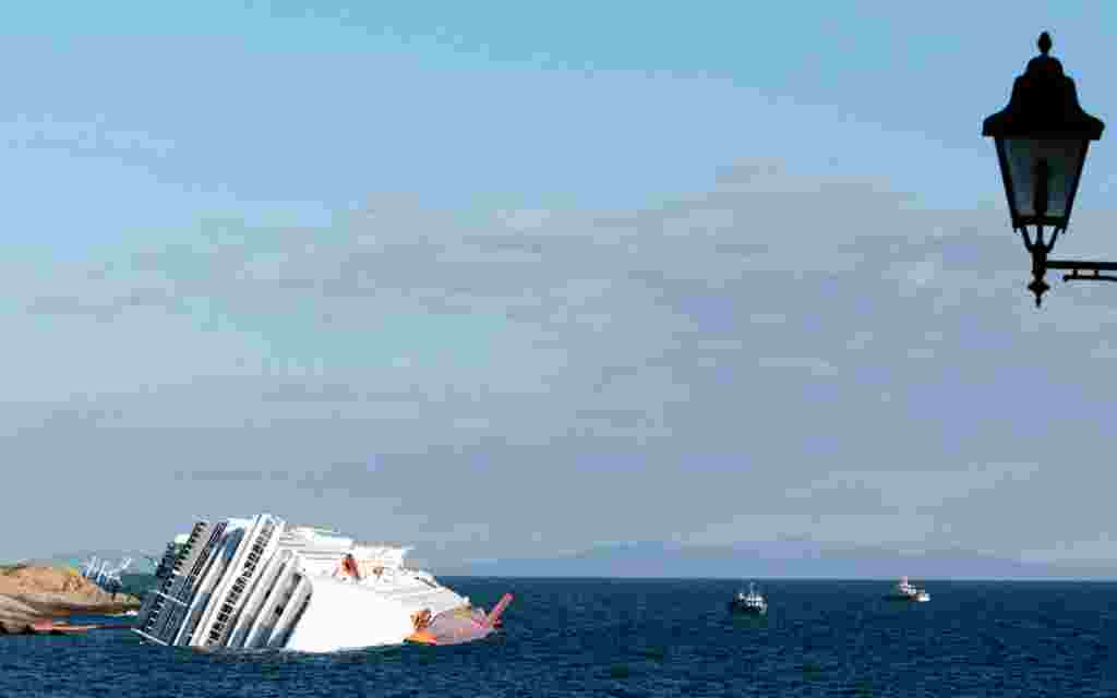 Kapal pesiar Costa Concordia masih terdampar di pesisir Pulau Giglio, Selasa, 17 Januari (AP).
