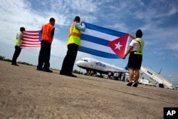 Airport workers receive the JetBlue flight 387 holding a United States, and Cuban national flag, on the airport tarmac in Santa Clara, Cuba, Aug. 31, 2016.